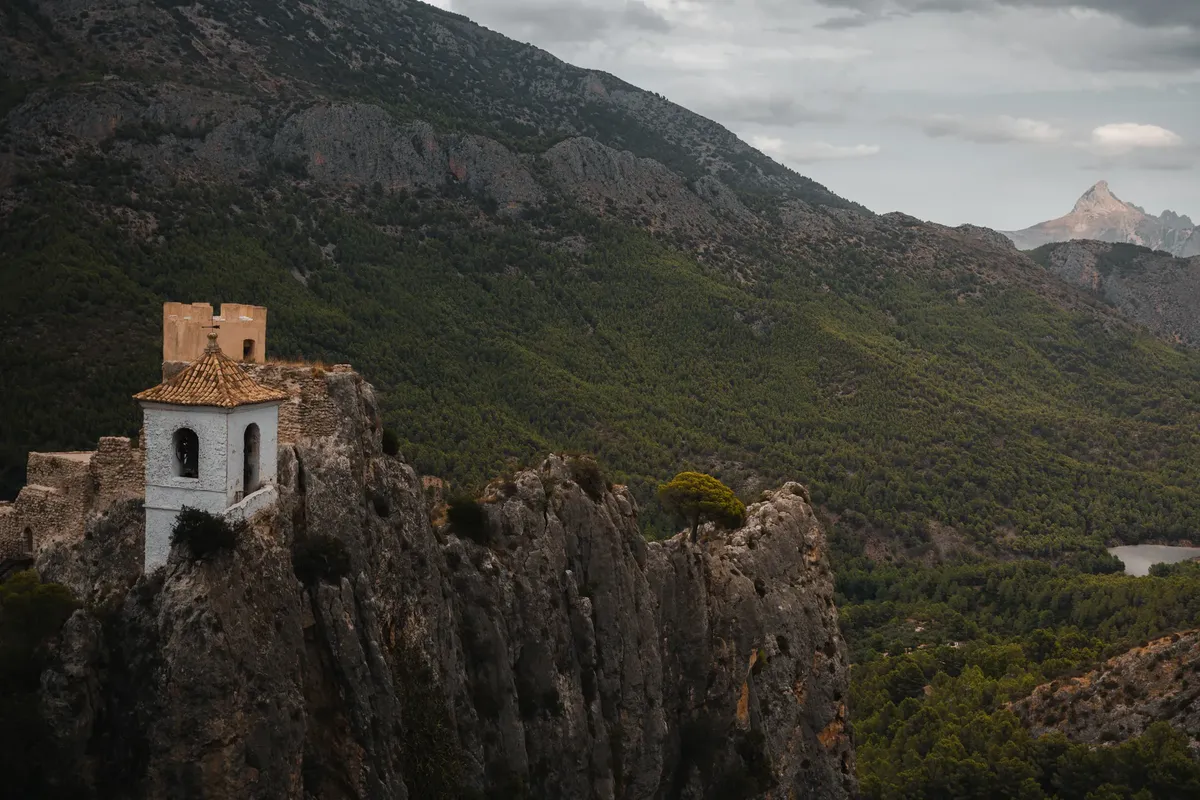 Scenic view of El Castell de Guadalest in Spain, surrounded by rugged mountains and lush forests.