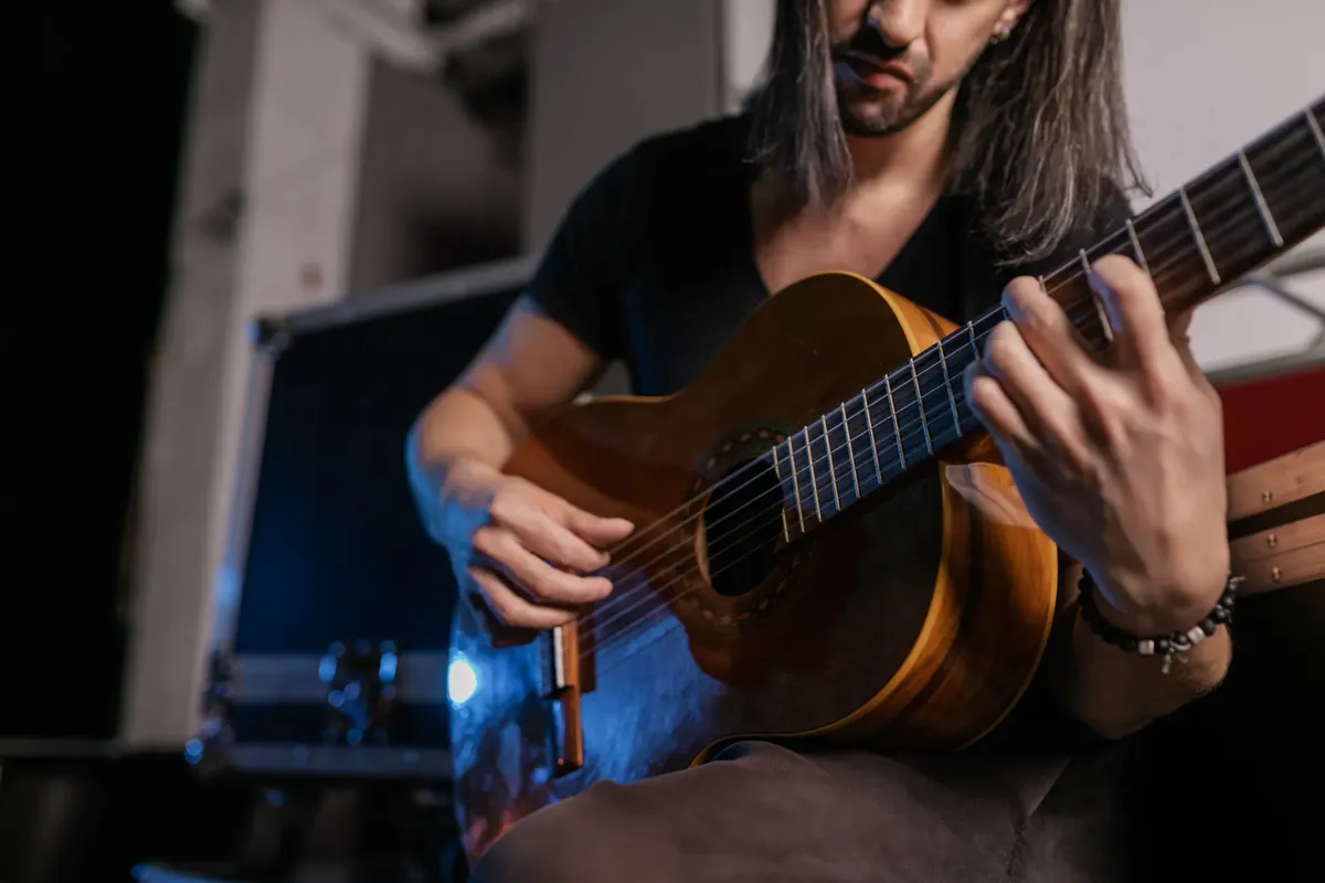 識別不能な演奏者があcousticギターを弦きっているライブパフォーマンスの中。
